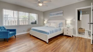 Un dormitorio con cama, mesitas de noche, ventilador de techo y ventana con persianas.