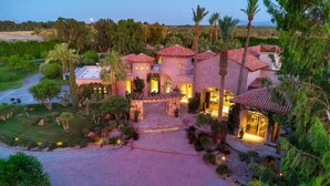 A large, luxurious villa with multiple towers, a central courtyard, and well-maintained gardens.