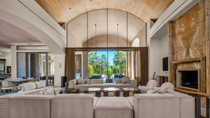 A spacious living room with a large sectional sofa, a fireplace, and a view of palm trees.