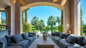 A spacious outdoor seating area with two sofas facing a view of palm trees and a clear sky.