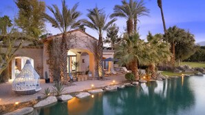 A luxurious villa with a swimming pool, outdoor seating, and a well-maintained garden.