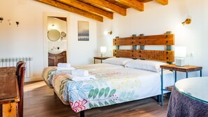 Un dormitorio con techo de madera, una cama con colcha estampada, una mesita de noche y un espejo.