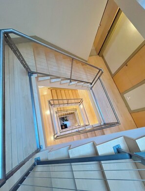 Eine moderne Treppe mit Metallgeländer, Holzstufen und Blick in einen Raum mit Bett und Nachttisch.