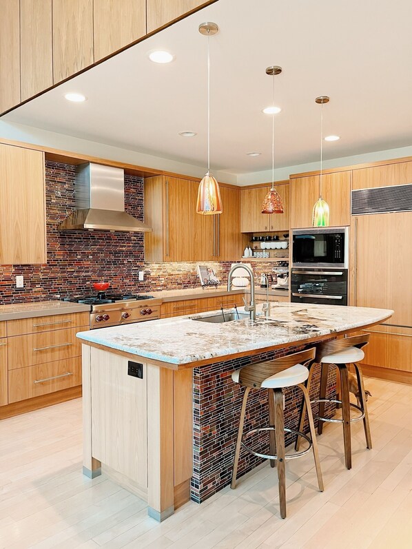 A modern kitchen with a central island, stainless steel appliances, and wooden cabinetry.
