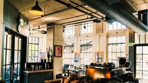 Ett rymligt café med stora fönster, en disk med utrustning för att göra kaffe och en tydlig utgångsskylt.