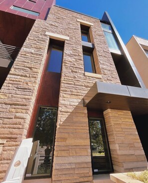 A modern building with a stone facade, large windows, and a flat roof.