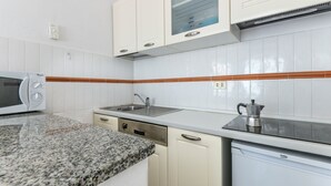 Eine Küche mit weißen Schränken, einer Granit Arbeitsplatte, einer eingebauten Mikrowelle, einem Spülbecken und einer Kaffeemaschine.