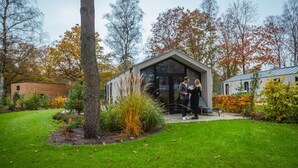 A modern building with a glass facade, surrounded by a well-maintained garden with grass and trees. - Chalet in a Residence Near sea (Arnhem)