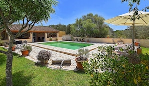 A pool area with a tiled deck, potted plants, and outdoor furniture.