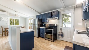 Une cuisine moderne dotée d’un îlot central, d’appareils électroménagers en acier inoxydable et de meubles de couleur bleue.
