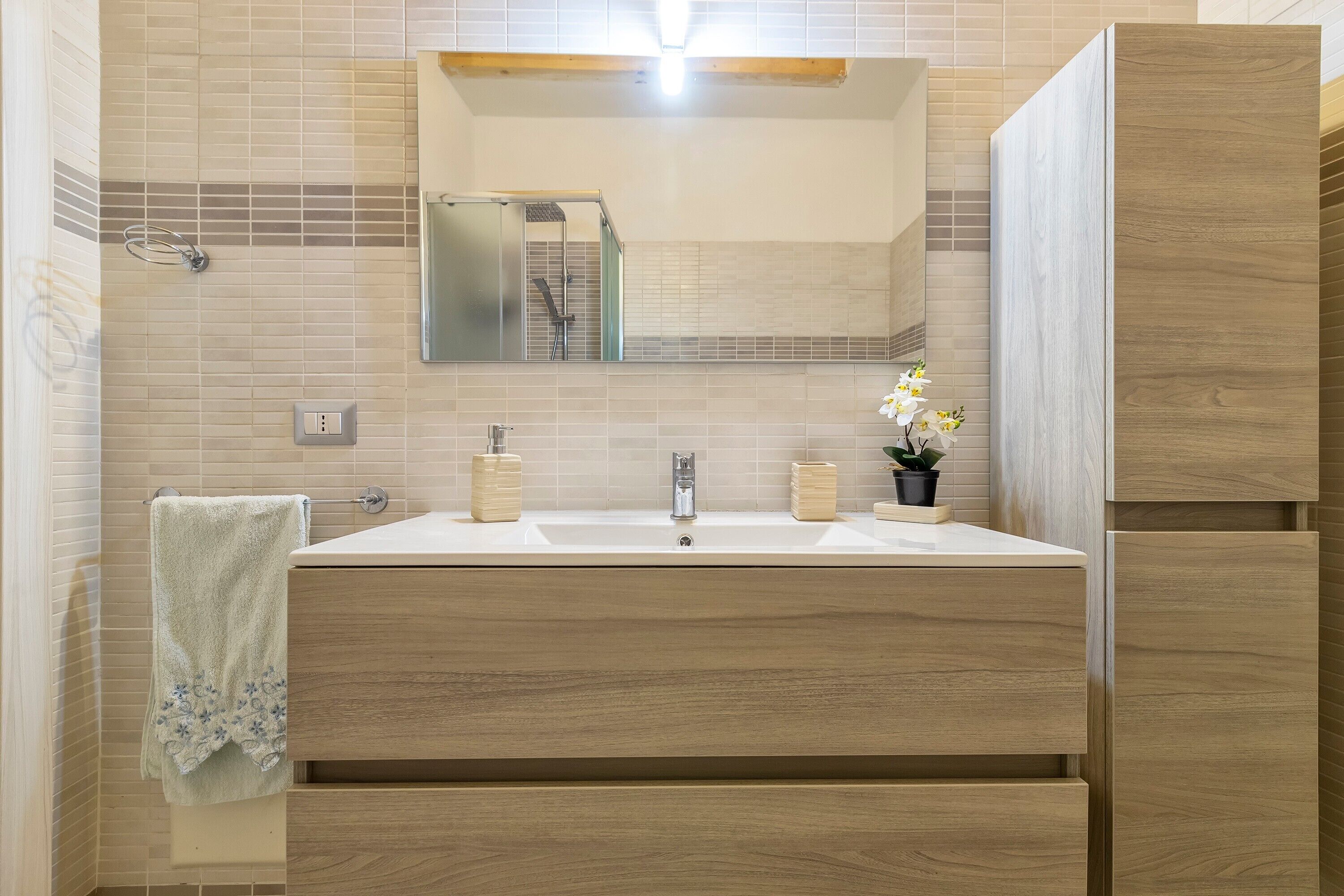 Une salle de bain équipée d’un lavabo, d’un miroir, d’un porte-serviettes et de meubles en bois.