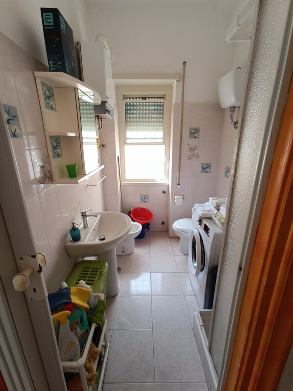 Une petite salle de bain comprenant un lavabo, des toilettes et un lave-linge.