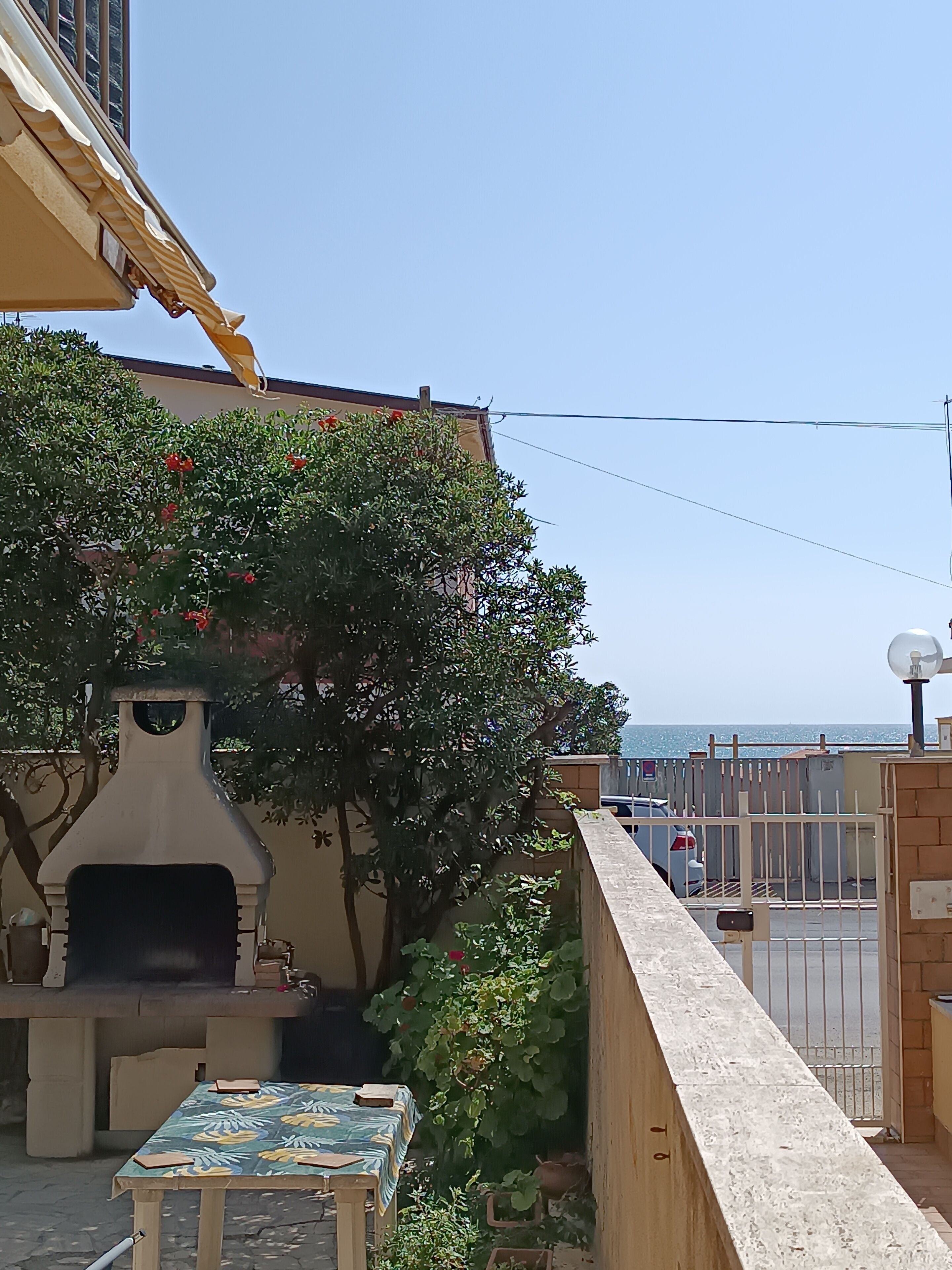 A patio with a barbecue grill, a table, and a view of the sea.