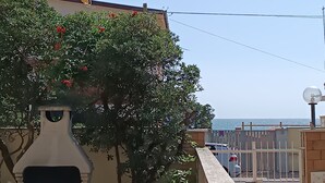 A patio with a barbecue grill, a table, and a view of the sea. - House by the sea with large equipped garden (Torvaianica)