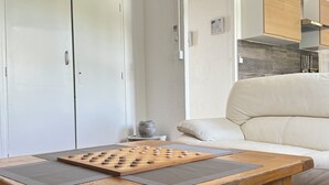 A wooden table with a chessboard, a grey mat, a grey vase, and a beige sofa in a modern living room with white walls and wooden cabinets. - Les Capucines - Tournon-sur-Rhône (Tournon-sur-Rhône)