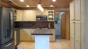 Una cucina con mobili in legno, un'isola centrale, un frigorifero e un forno a microonde.