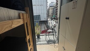 Una habitación pequeña y estrecha con una cama litera, una mesita y un armario.