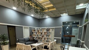 Un área de espera moderna con zona de estar, una mesita y una estantería.