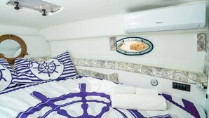 Ein Schlafzimmer mit einem Bett, einem runden Spiegel, einem Deckenventilator und einer Tesla Klimaanlage.