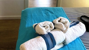 Ein Zimmer mit einem Bett, einem Esstisch mit Stühlen und Blick durch eine offene Tür.