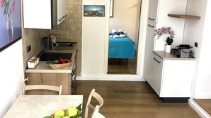 Eine kleine Küche mit Essbereich, einem Spülbecken und Blick in ein Schlafzimmer.