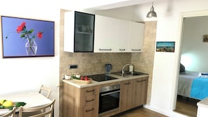 Eine kompakte Küche mit Holzausstattung, einem eingebauten Backofen, einer Spüle und einem Essbereich mit Tisch und Stühlen.