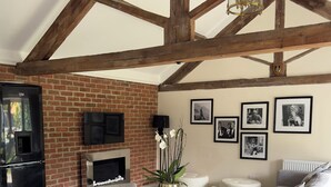 A dining area with a round table, four chairs, a black refrigerator, a brick fireplace, and a sofa. - The Luxury Annex at Barmby Moor House (York)