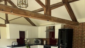 A modern kitchen with white cabinets, a black refrigerator, and a dining area with a round table and chairs. - The Luxury Annex at Barmby Moor House (York)