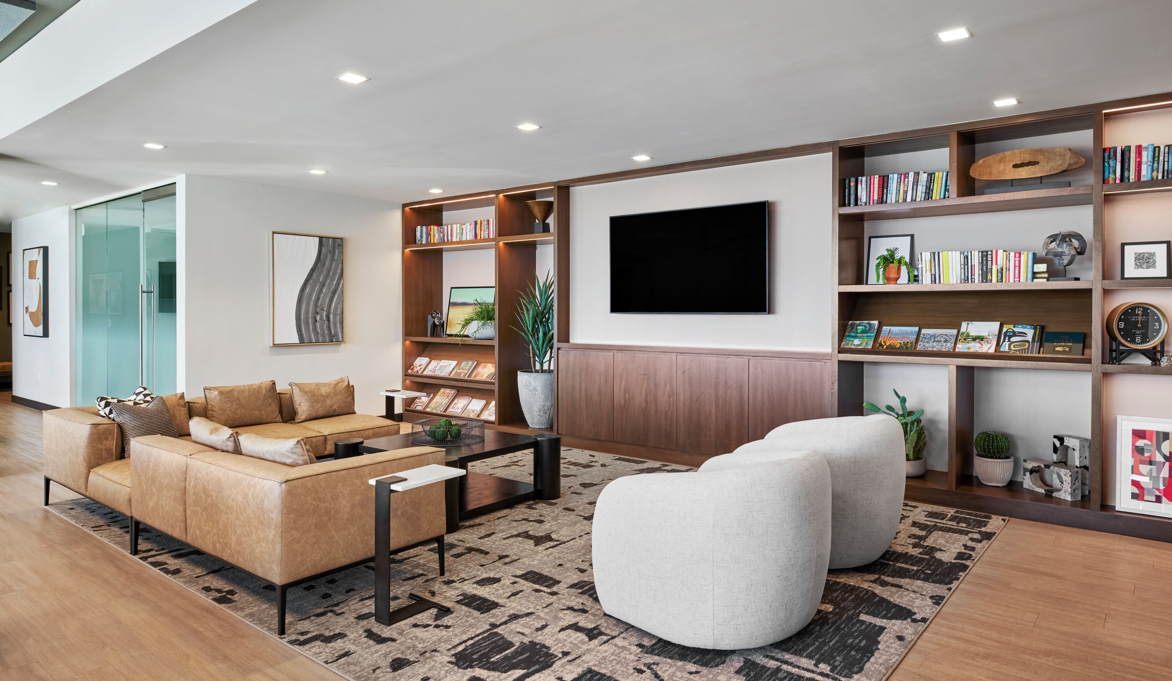 A modern living room with a sofa, ottoman, coffee table, and bookshelves.