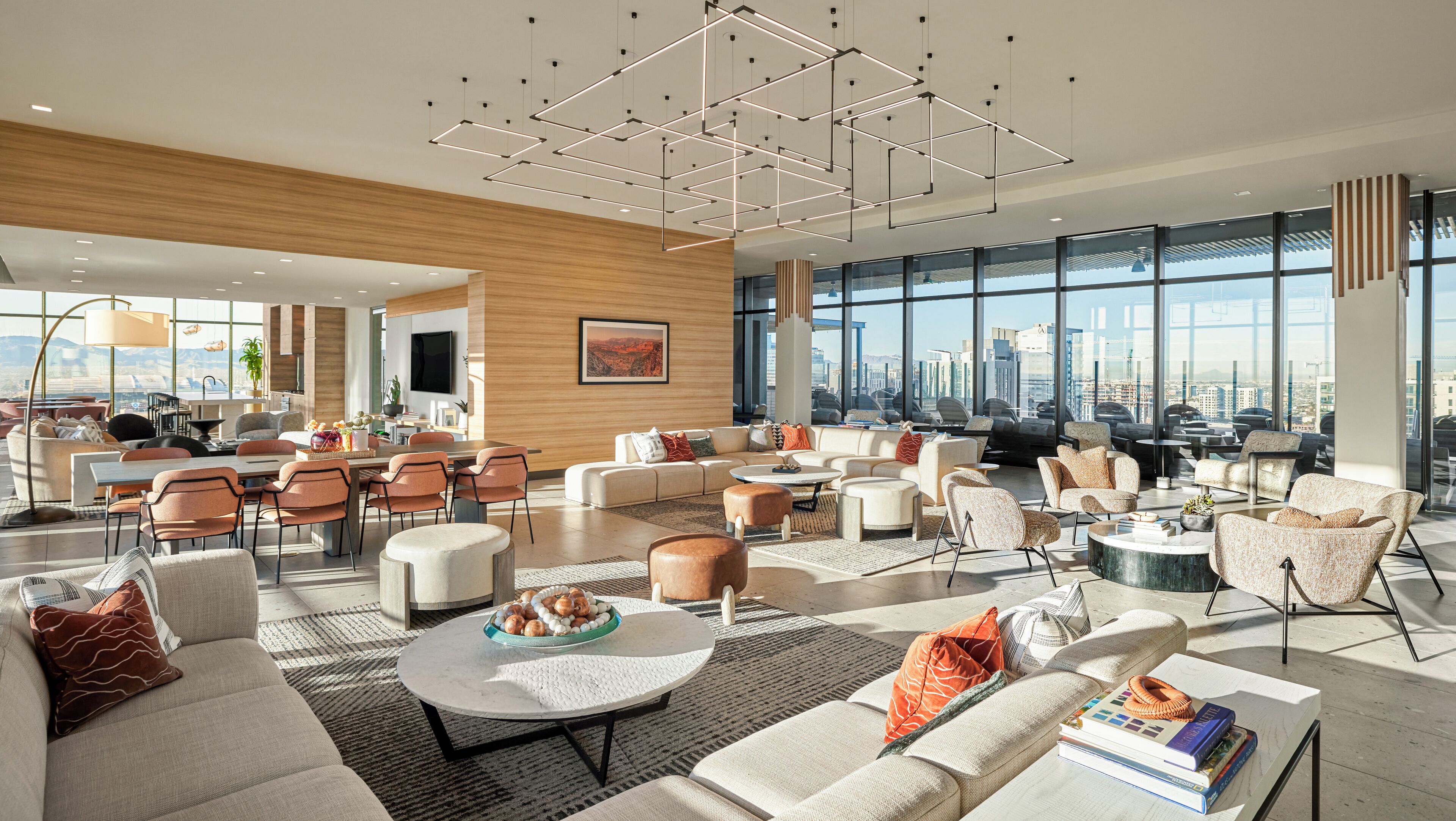 A spacious, modern living area with a city view, featuring a mix of sofas, chairs, and a dining area.