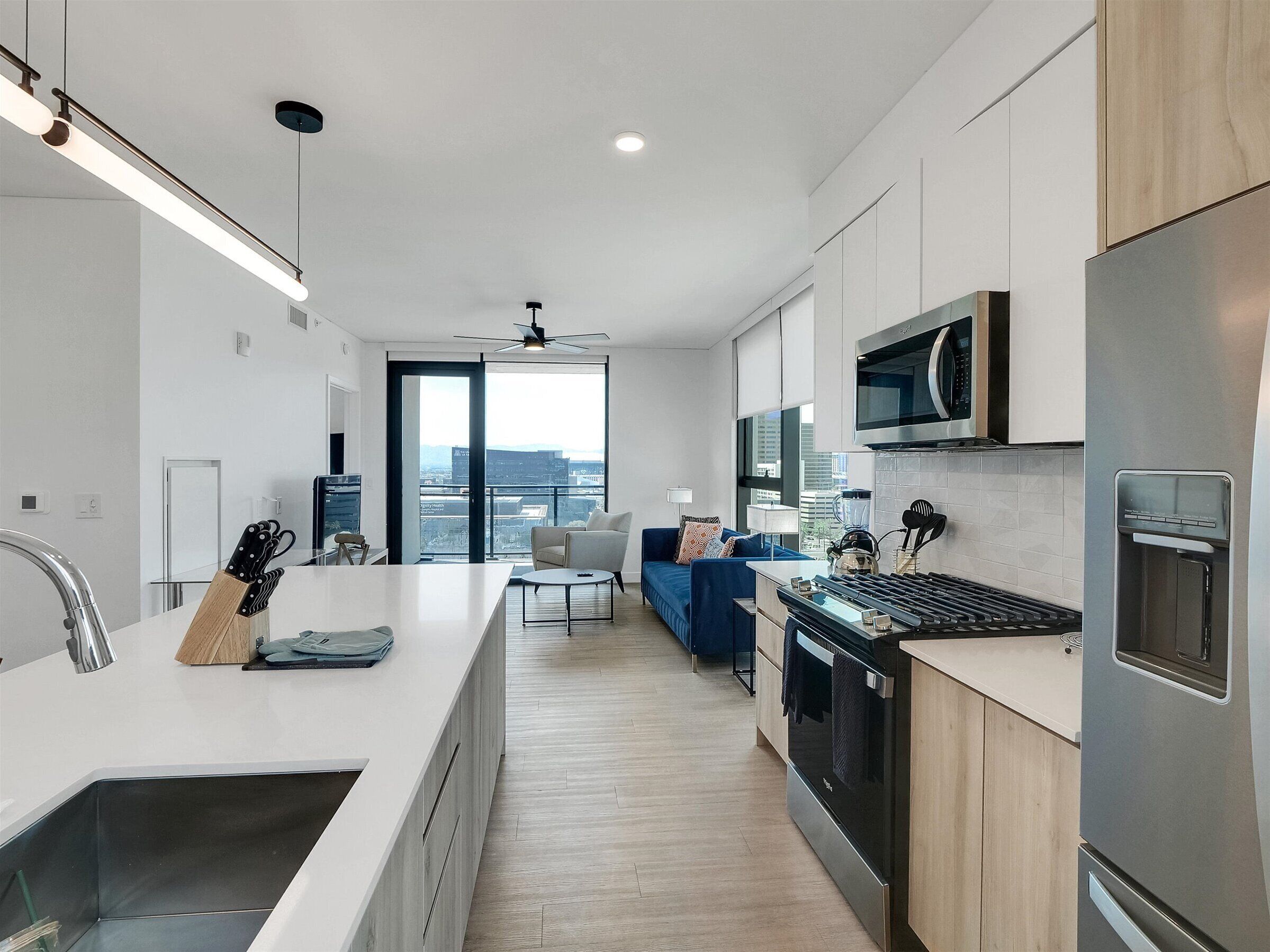 A modern kitchen with a central island, stainless steel appliances, and a city view.