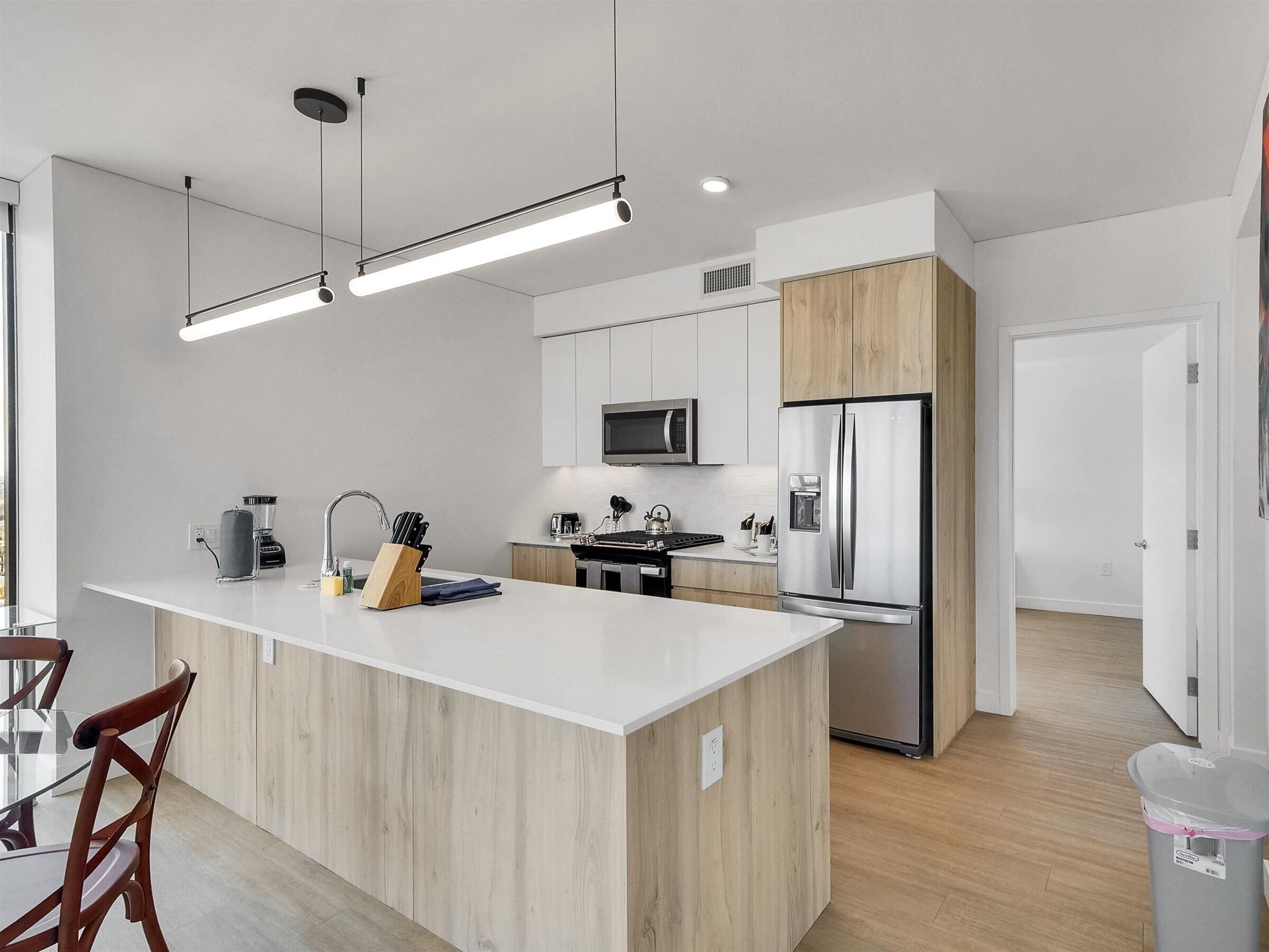 Une cuisine moderne dotée d’un îlot central, d’appareils électroménagers en acier inoxydable et d’un design minimaliste.