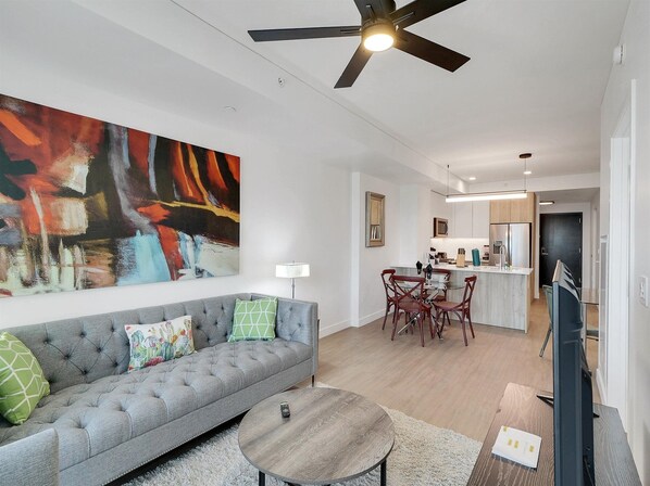 A modern living room with a grey sofa, a coffee table, and a painting on the wall.
