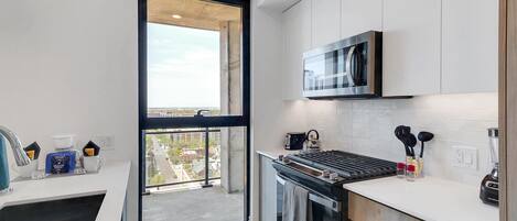A modern kitchen with a built-in oven, microwave, and a large window offering a city view.