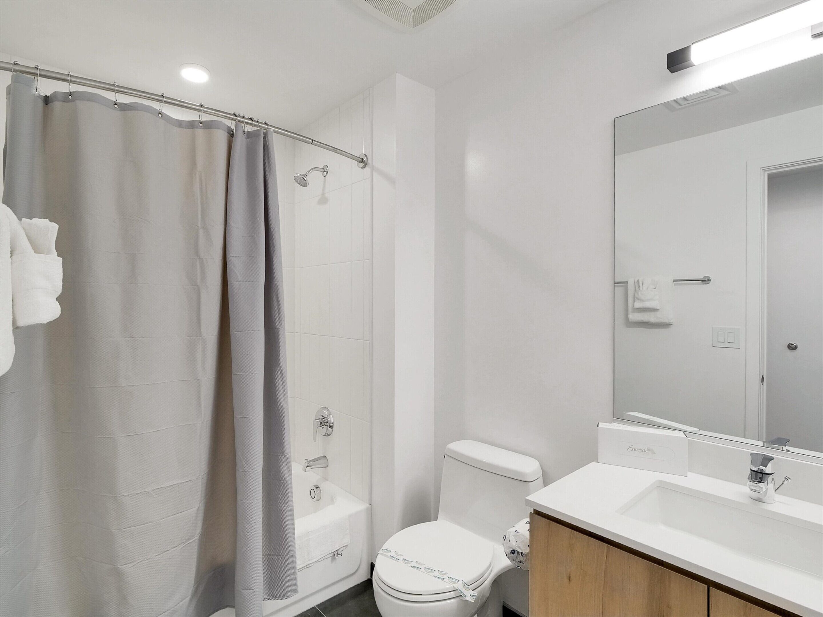 A modern bathroom with a shower, toilet, and sink.