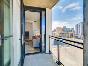 A balcony with a city view, a sofa, a TV, and a lamp.
