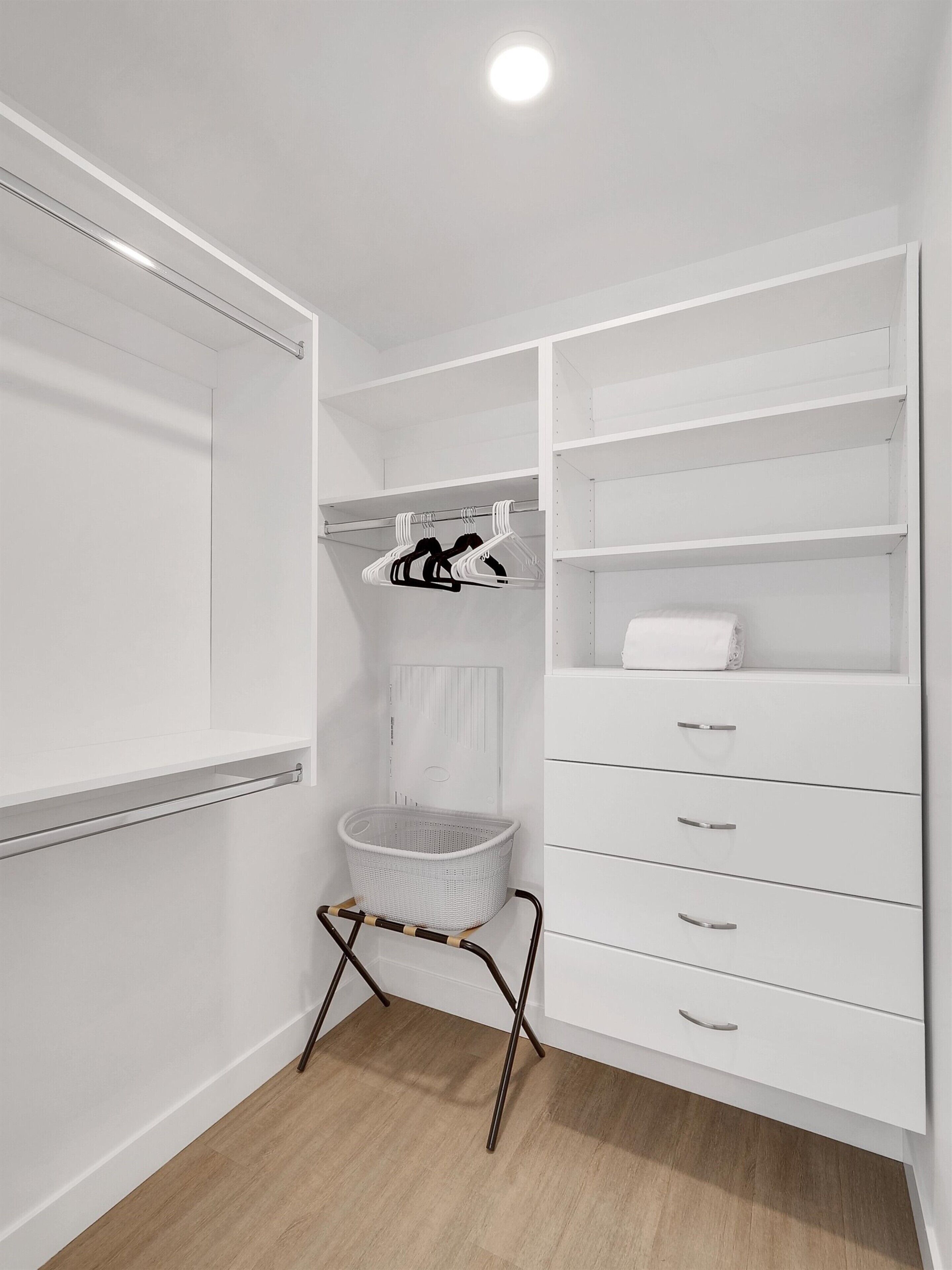 A white walk-in closet with shelves, drawers, and a hanging rack.