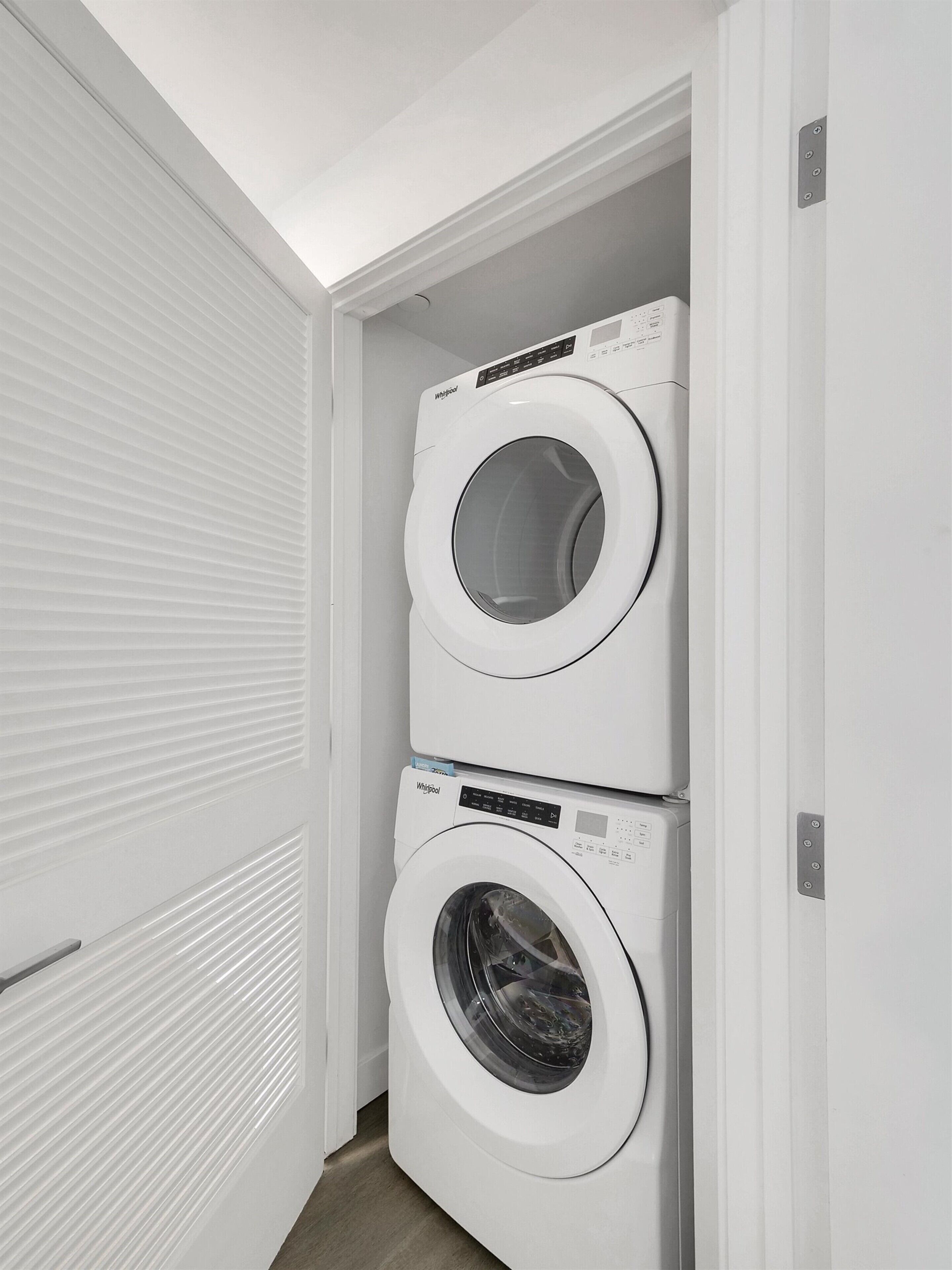A laundry room with two stacked Whirlpool front-loading washing machines.