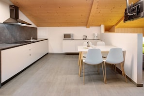 Una cocina moderna con techo de madera, estufa integrada, microondas y cafetera.
