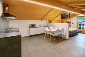 A modern kitchen with a dining area, wooden ceiling, and a view of the outdoors.