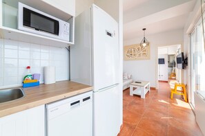 A modern kitchen with a microwave, refrigerator, and dishwasher. There is a wooden countertop, a sink, and a window with a view. - Apartment 'Fabuloso Atico Con Vistas Al Mar' with Sea View, Wi-Fi and Air Conditioning (Carboneras)