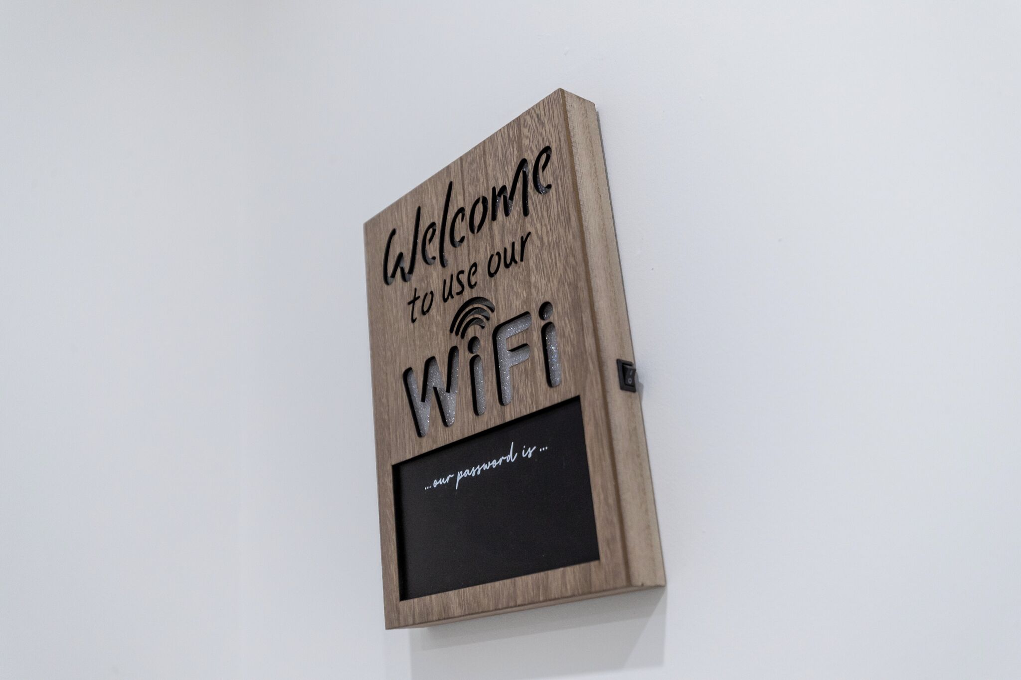 Un panneau en bois portant l’inscription « Bienvenue, utilisez notre réseau Wi-Fi » et, en dessous, un tableau noir.