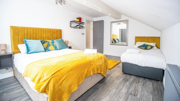 Un dormitorio moderno con una cama grande, una cama más pequeña y un vestidor.
