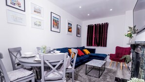 Una sala de estar moderna con comedor, que incluye un sofá, sillas, chimenea y obras de arte en las paredes.