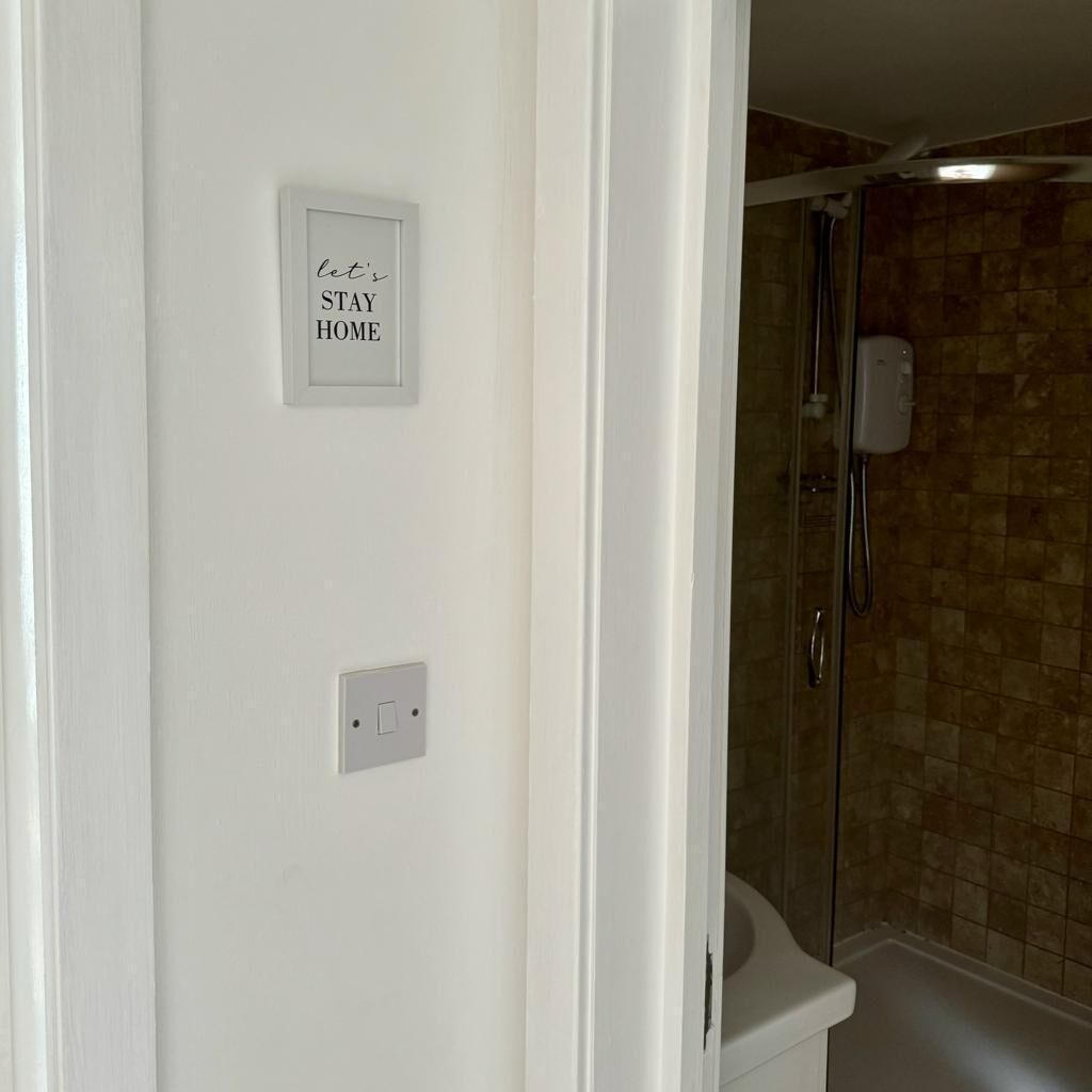 A bathroom with a shower, a towel rack, and a sign that reads "let's STAY HOME".