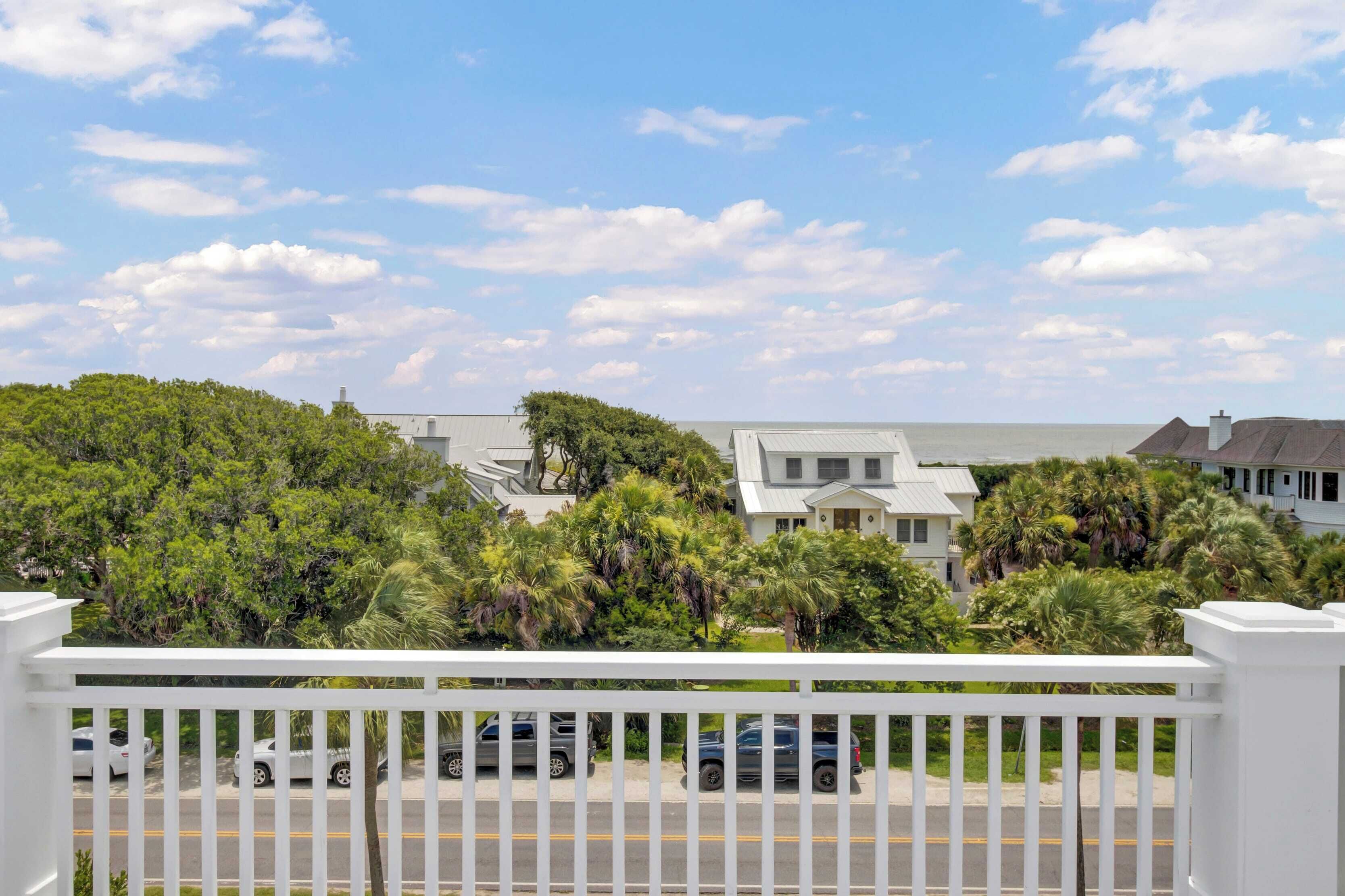 A residential area with houses, a white fence, and parked cars.