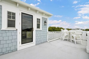 A white house with a covered patio, a white fence, and a table with chairs.