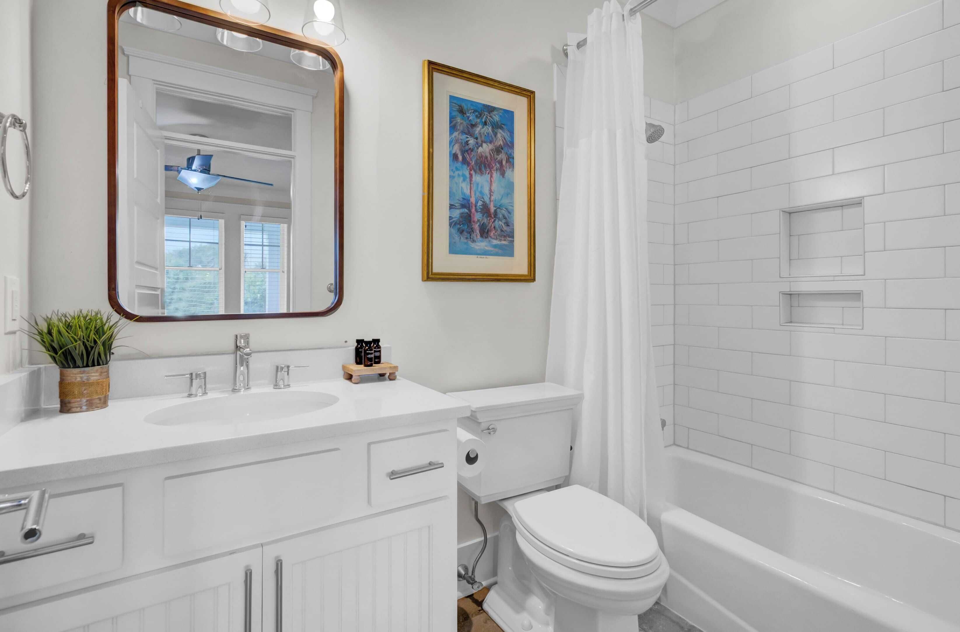 A bathroom with a white sink, mirror, toilet, and bathtub.