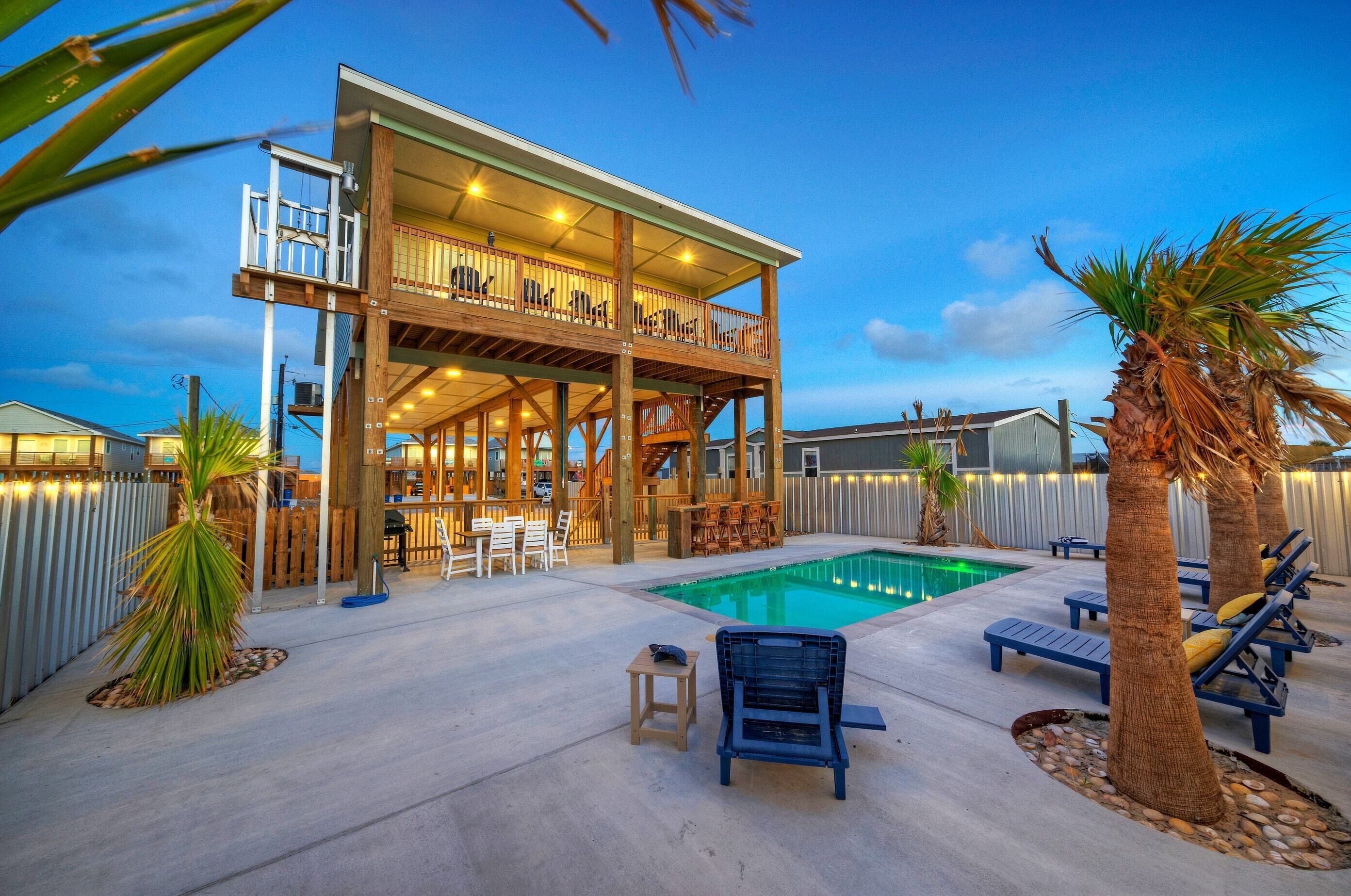 A two-story house with a balcony, a swimming pool, and outdoor seating.