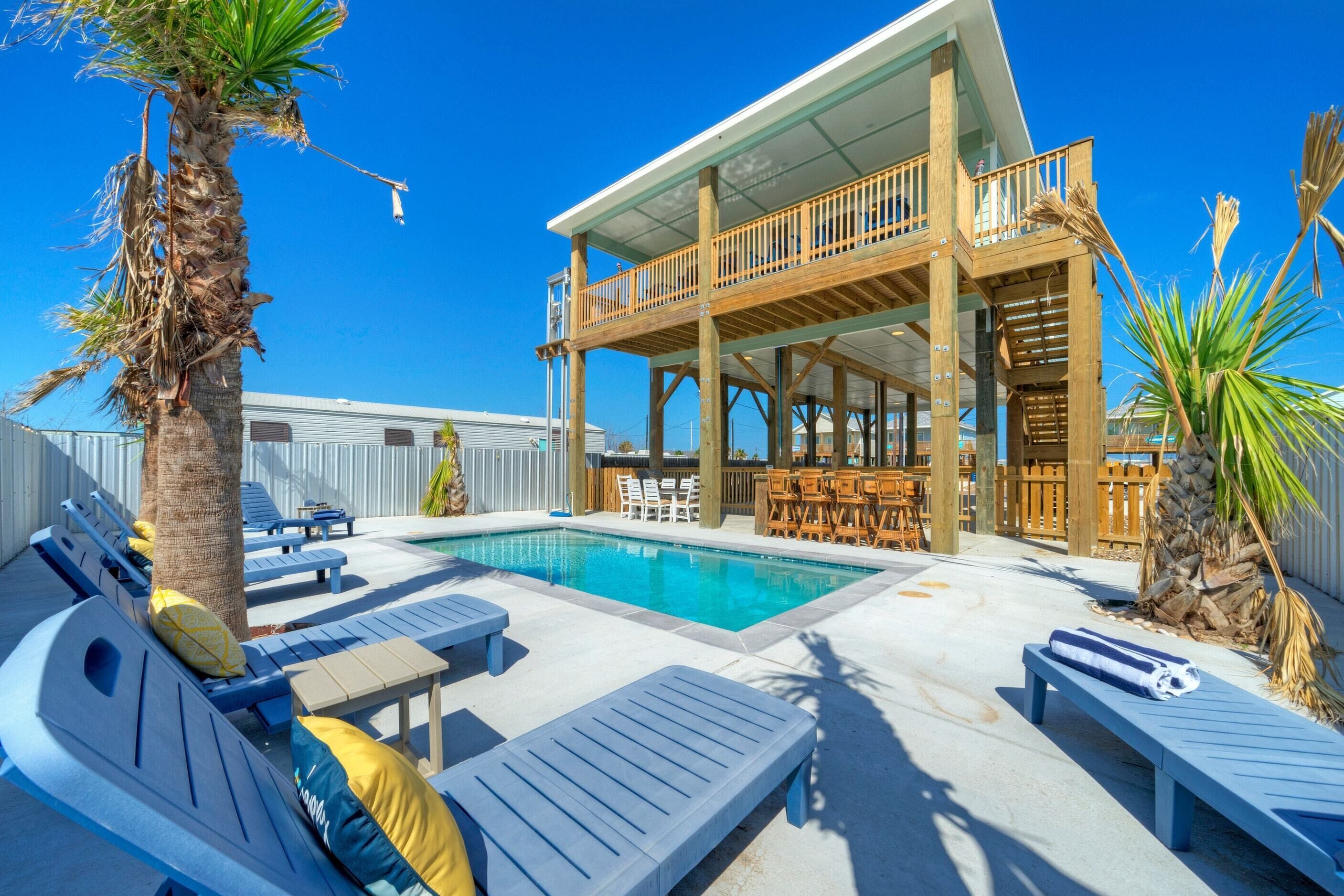 A poolside area with lounge chairs, a wooden deck, and a covered seating area.